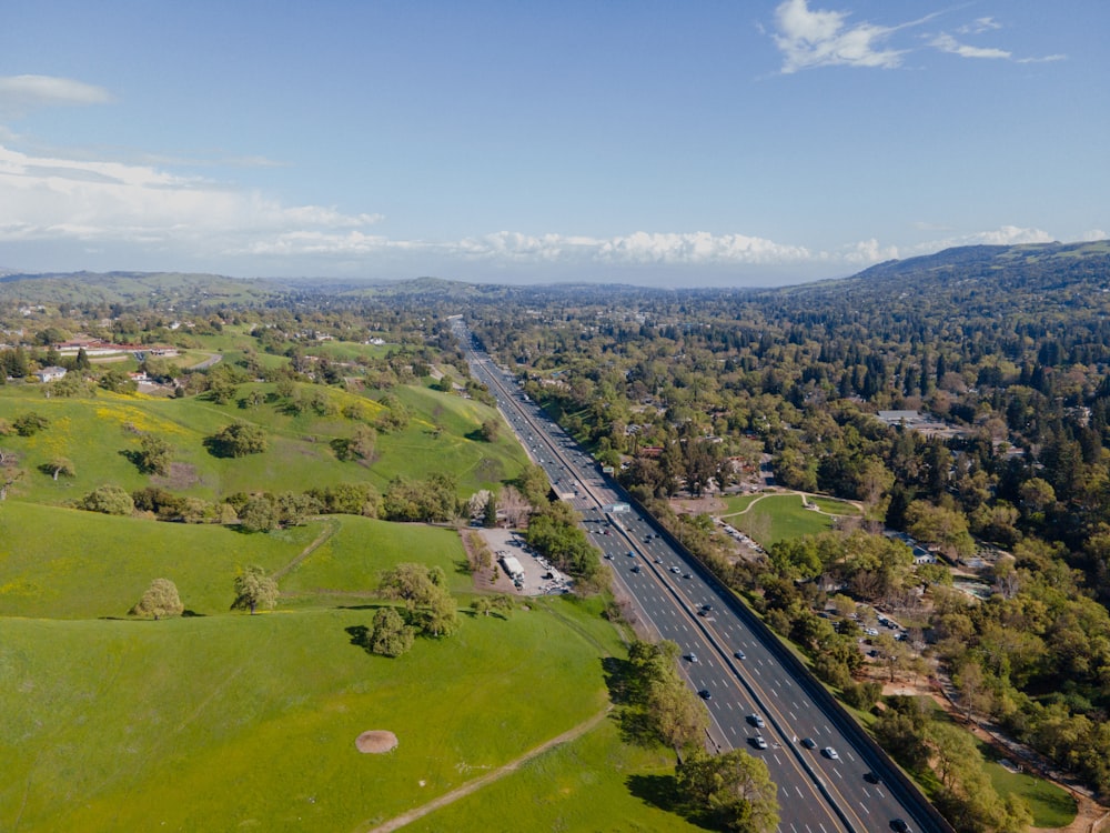 an aerial view of a highway in the middle of a lush green field