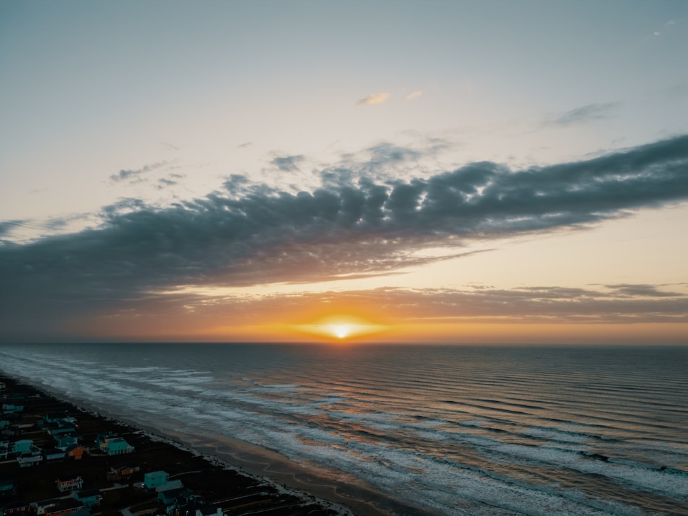 the sun is setting over the beach and the ocean