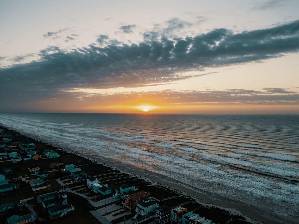 the sun is setting over the beach and houses