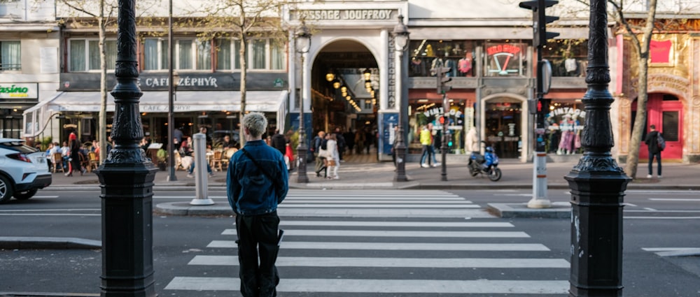 a man standing at a crosswalk in the middle of a city