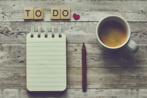 a cup of coffee next to a notepad with the words to do on it