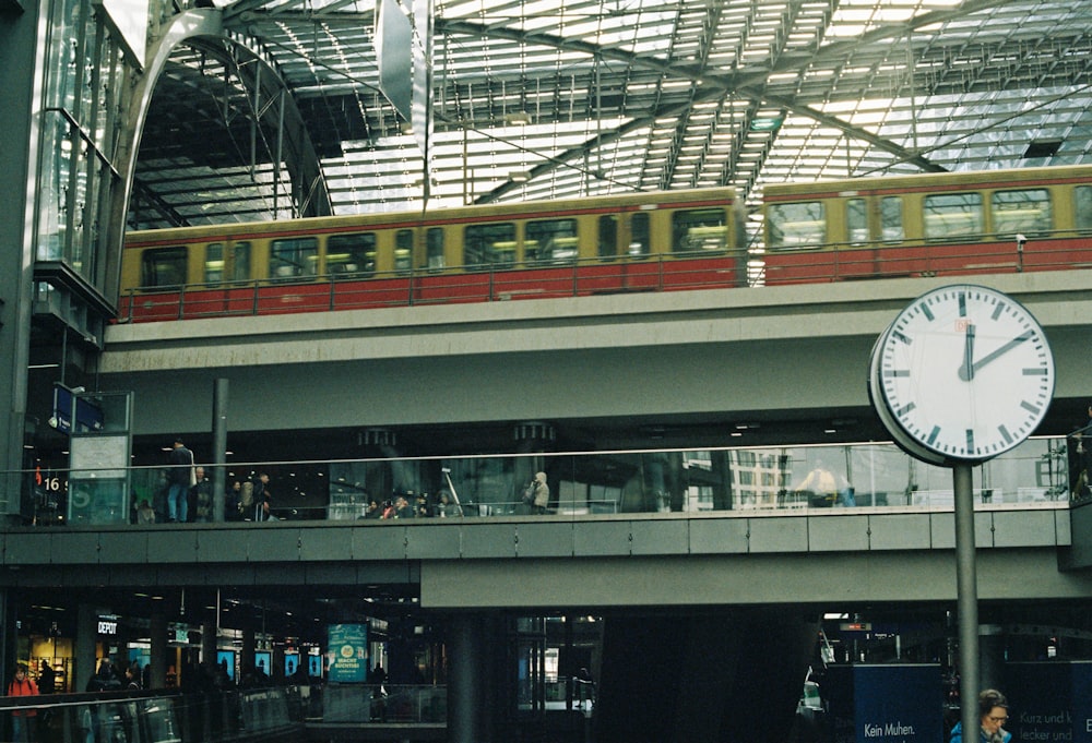 a clock in a train station with a train on the tracks