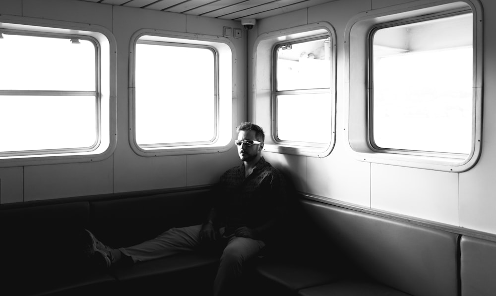 a man sitting on a bench next to two windows