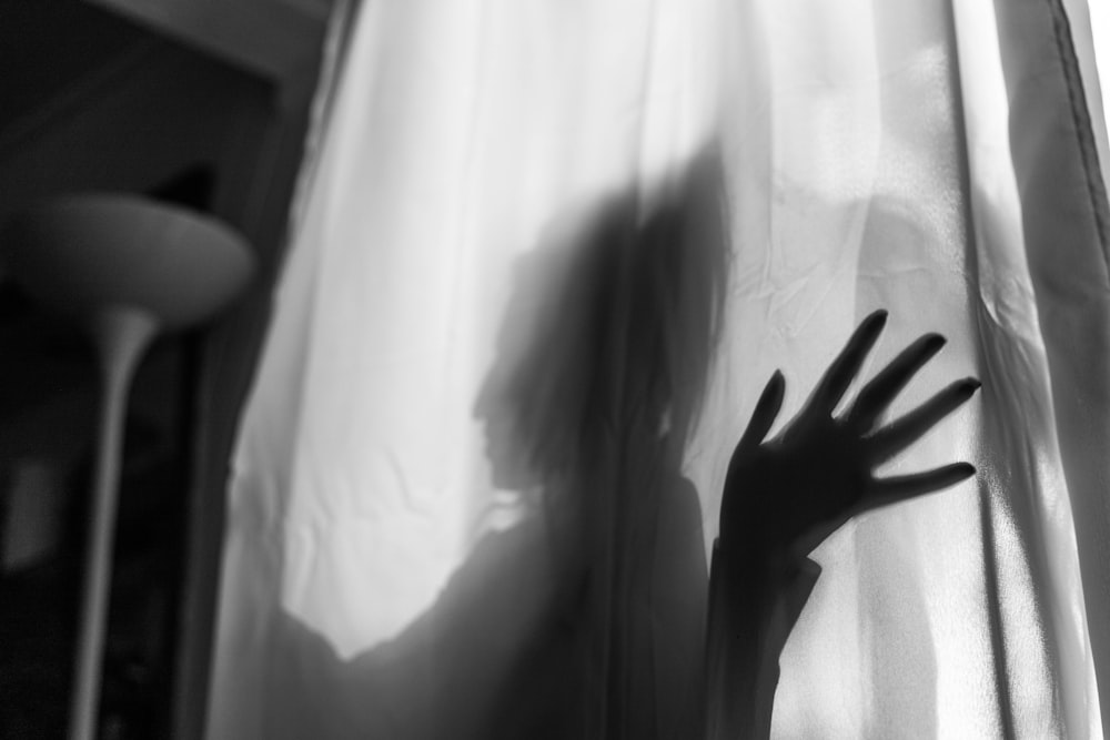 a shadow of a hand on a curtain