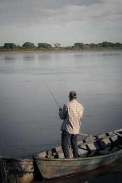a man standing on a boat holding a fishing rod