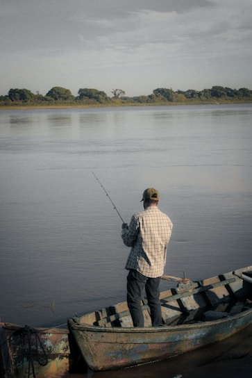 a man standing on a boat holding a fishing rod