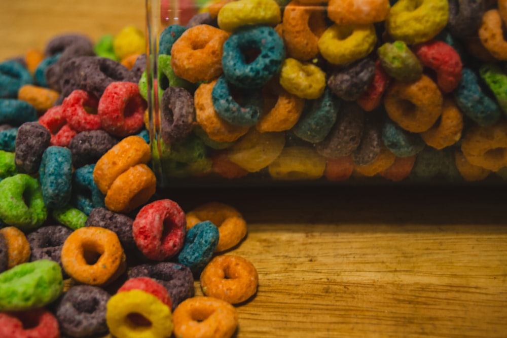a jar filled with colorful cereal sitting on top of a wooden table