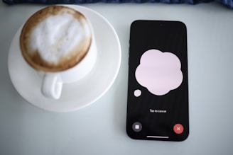 a cup of coffee next to a cell phone