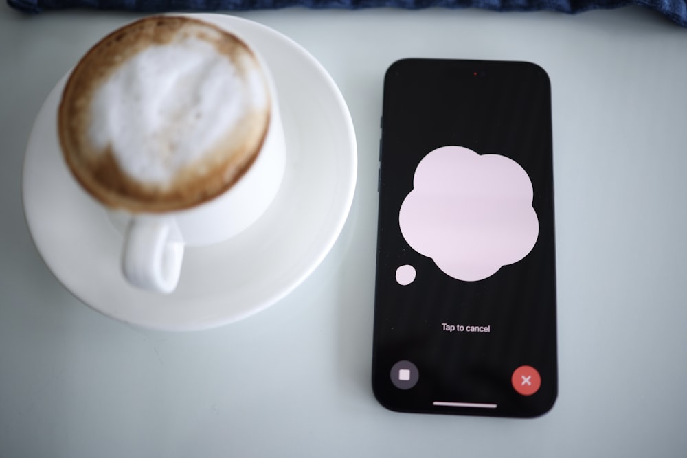 a cup of coffee next to a cell phone