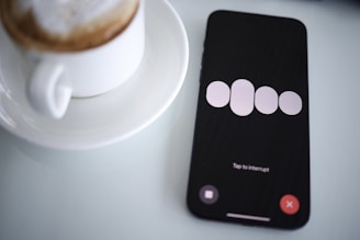 a cell phone sitting next to a cup of coffee