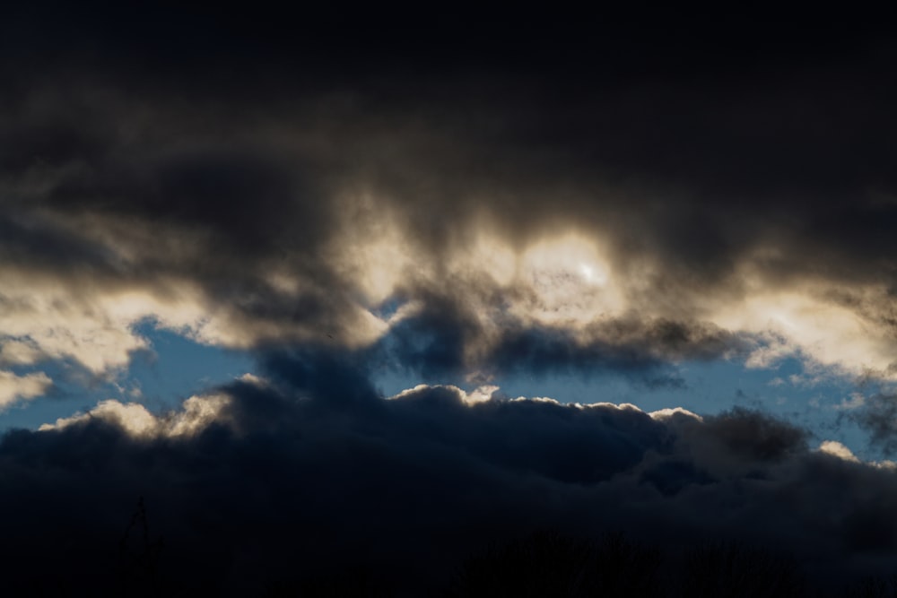 a dark sky with clouds and a plane flying in the sky