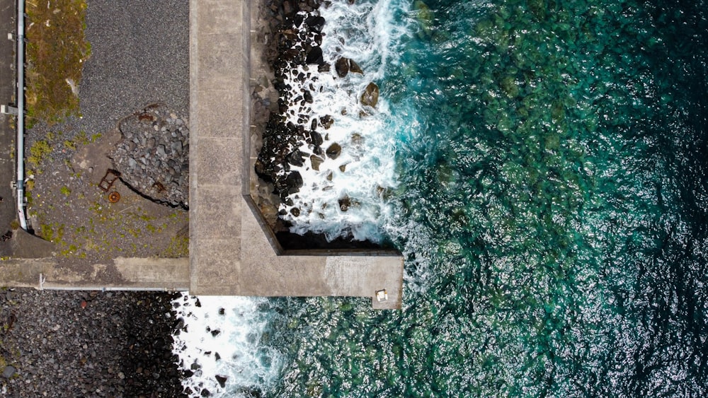 an aerial view of the ocean and a concrete walkway