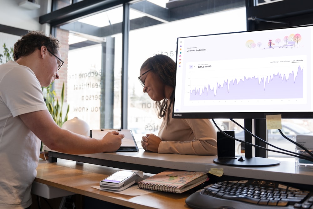 a man and woman sitting at a desk in front of a computer