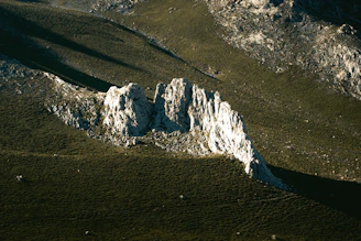 a large white rock sitting on top of a lush green hillside