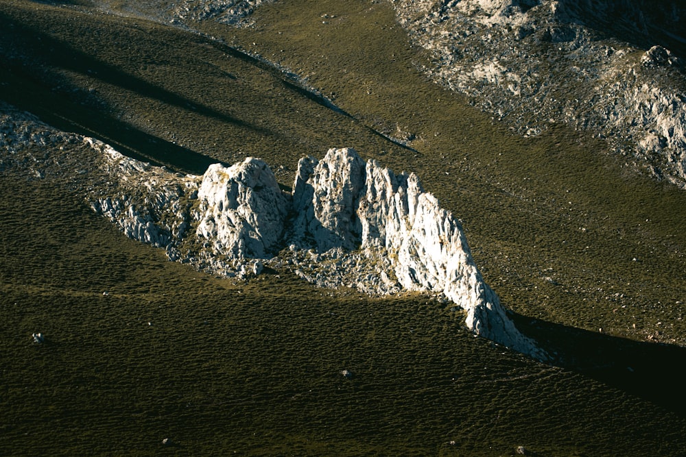 a large white rock sitting on top of a lush green hillside