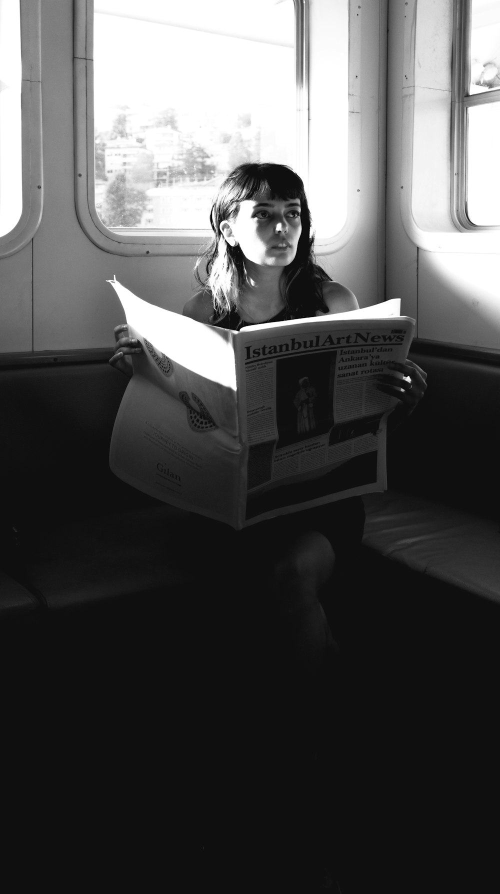 a woman sitting on a bench reading a newspaper