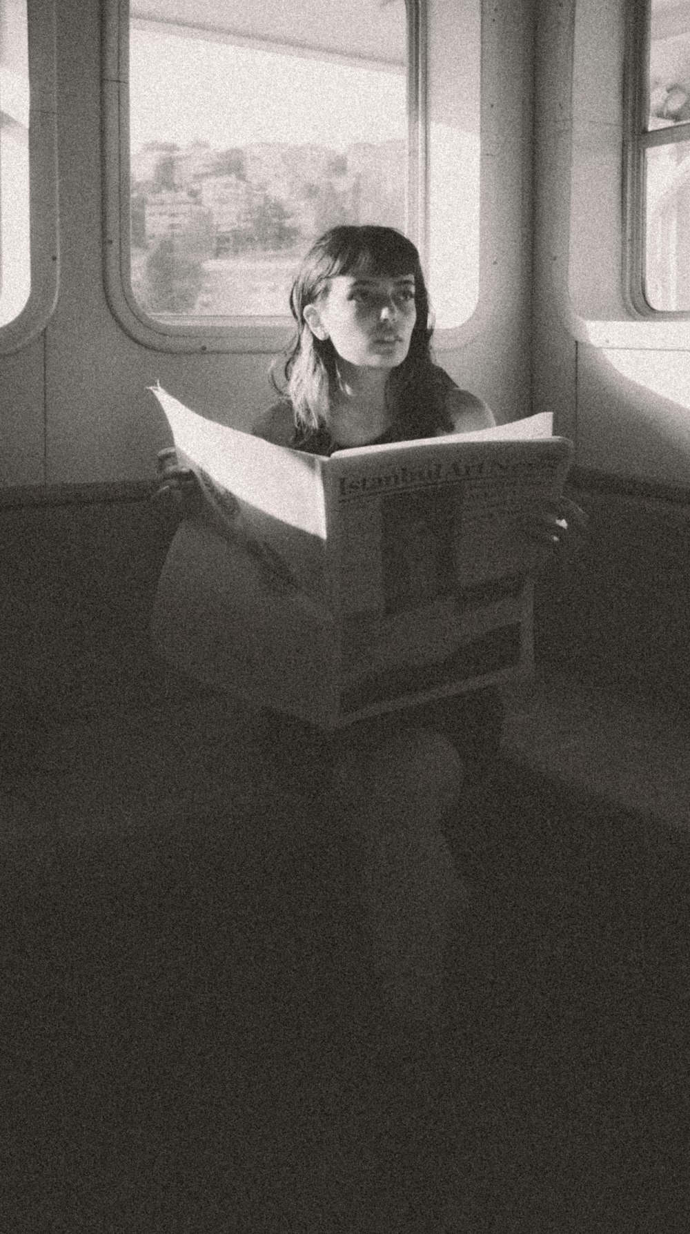 a woman sitting on a train reading a book