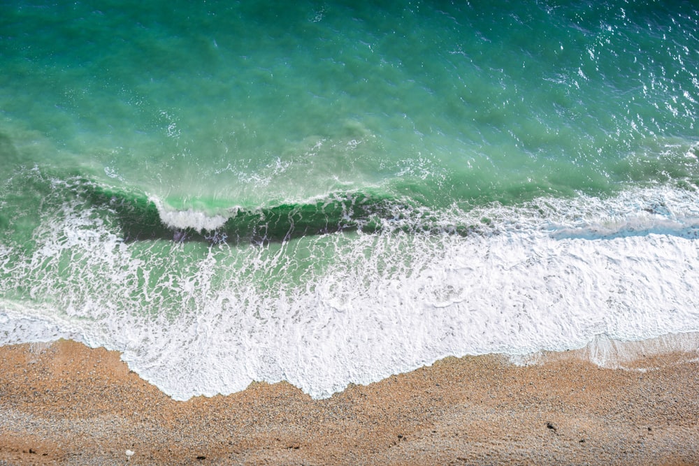 an aerial view of a beach with a wave coming in