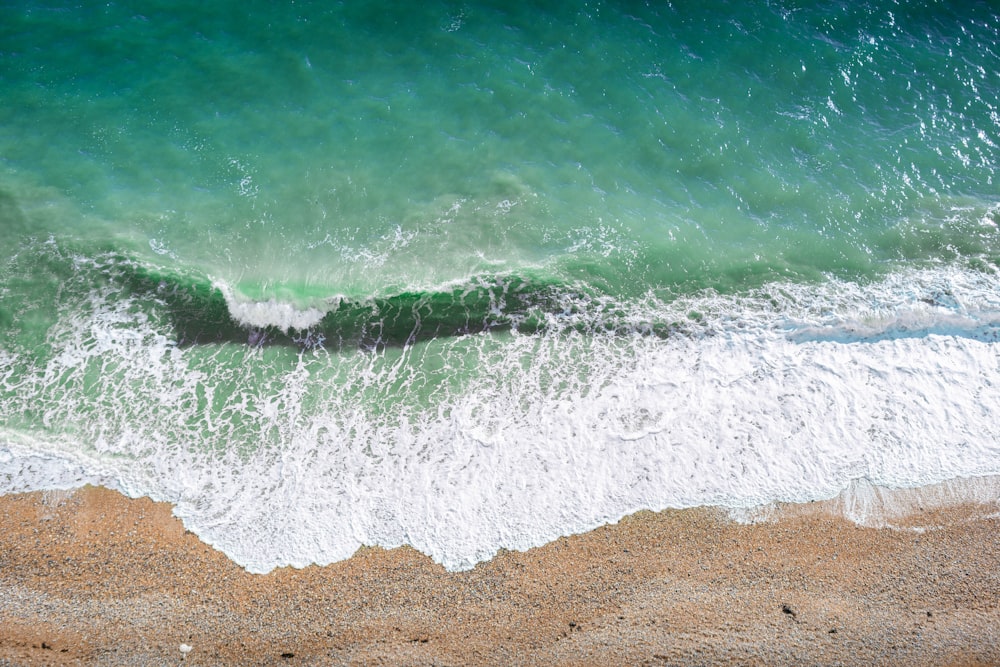 une vue aérienne d’une plage avec une vague qui arrive