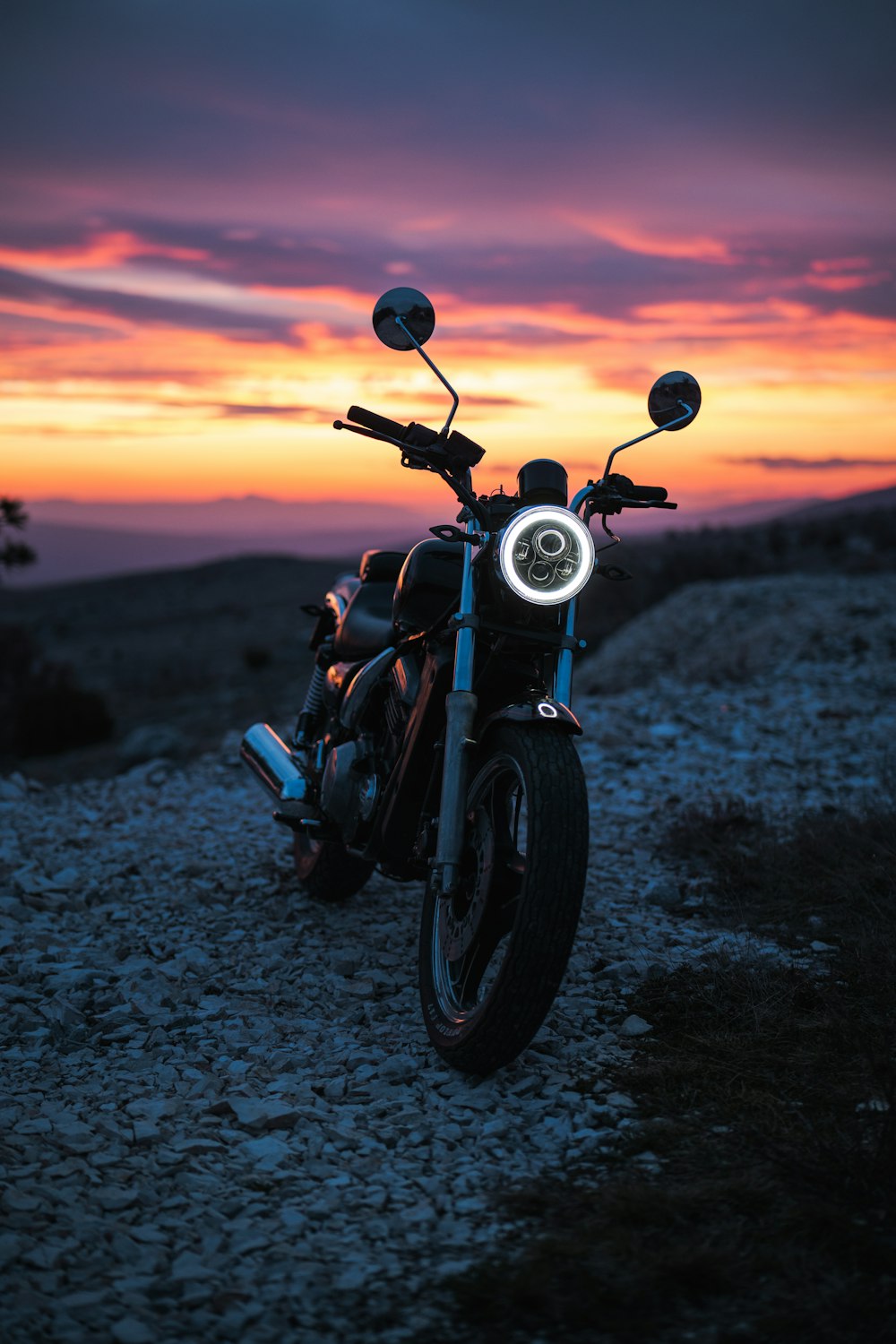 a motorcycle parked on top of a rocky hill