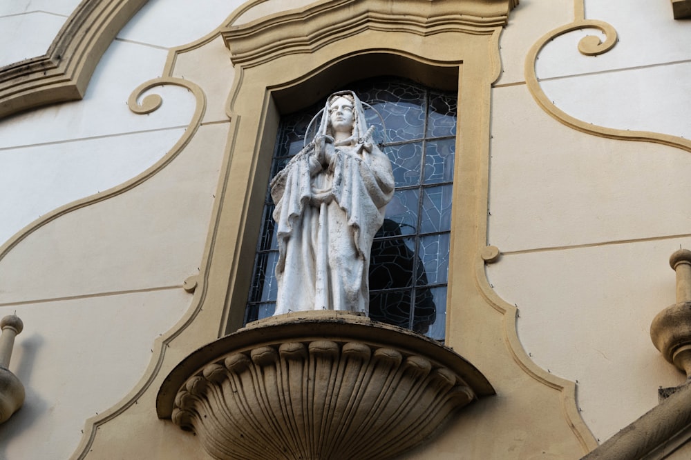 uma estátua de uma mulher em uma janela de um edifício