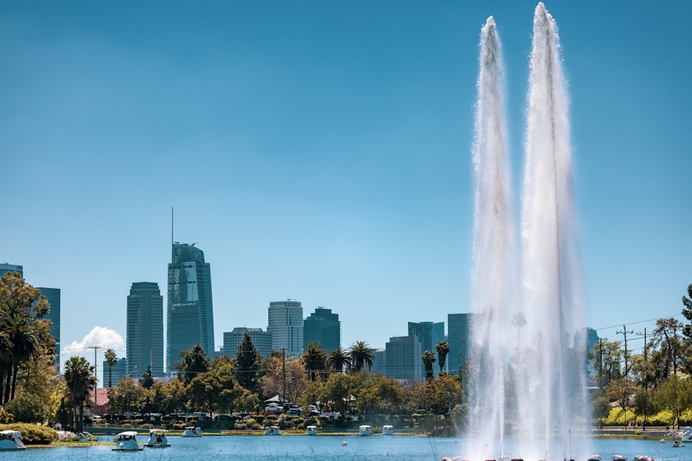 a large fountain spewing water into the air in front of a city skyline