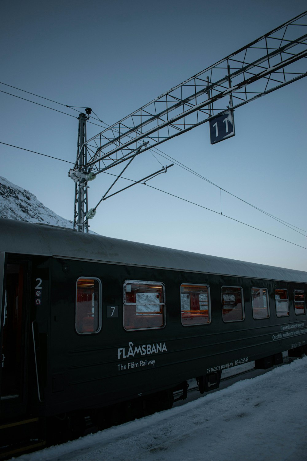 a black train traveling down train tracks next to a snow covered hillside