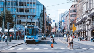 a blue bus driving down a street next to tall buildings