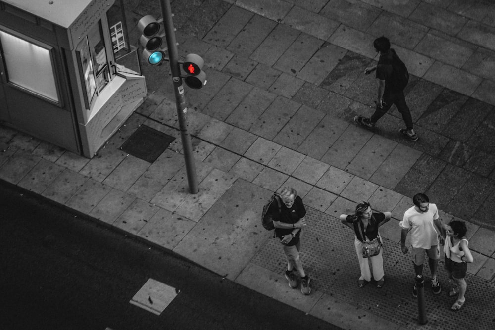 a group of people standing on a sidewalk next to a traffic light