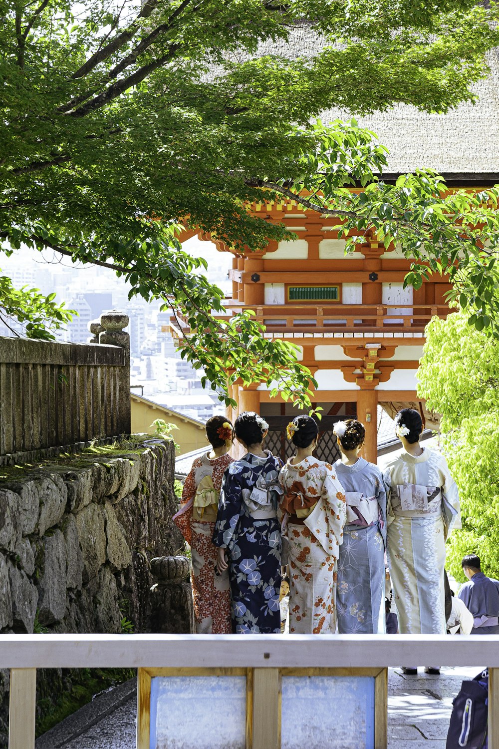 a group of women in kimonos standing in front of a pagoda