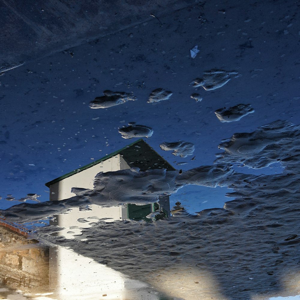 a reflection of a house in a puddle of water