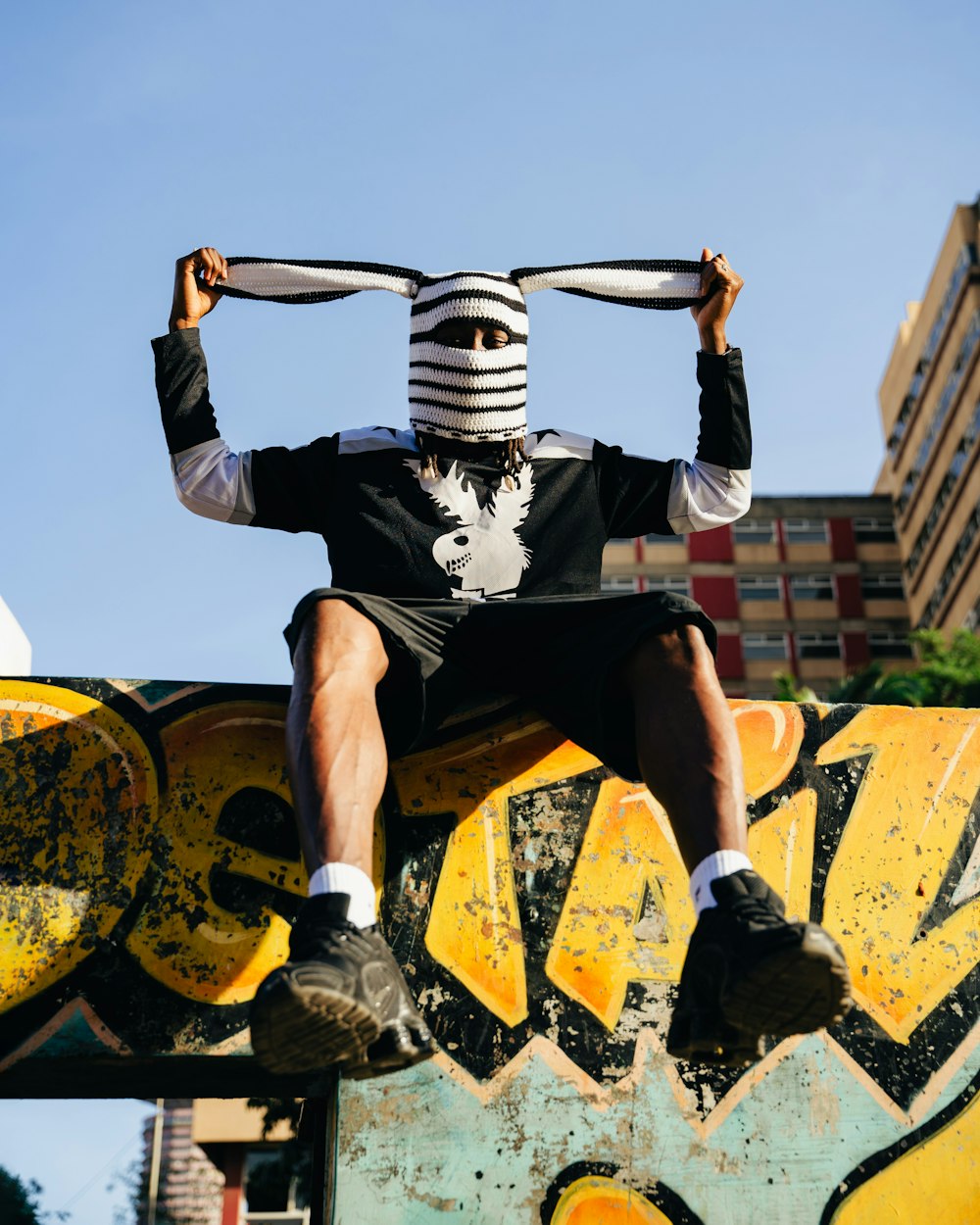 a man sitting on top of a skateboard wearing a mask