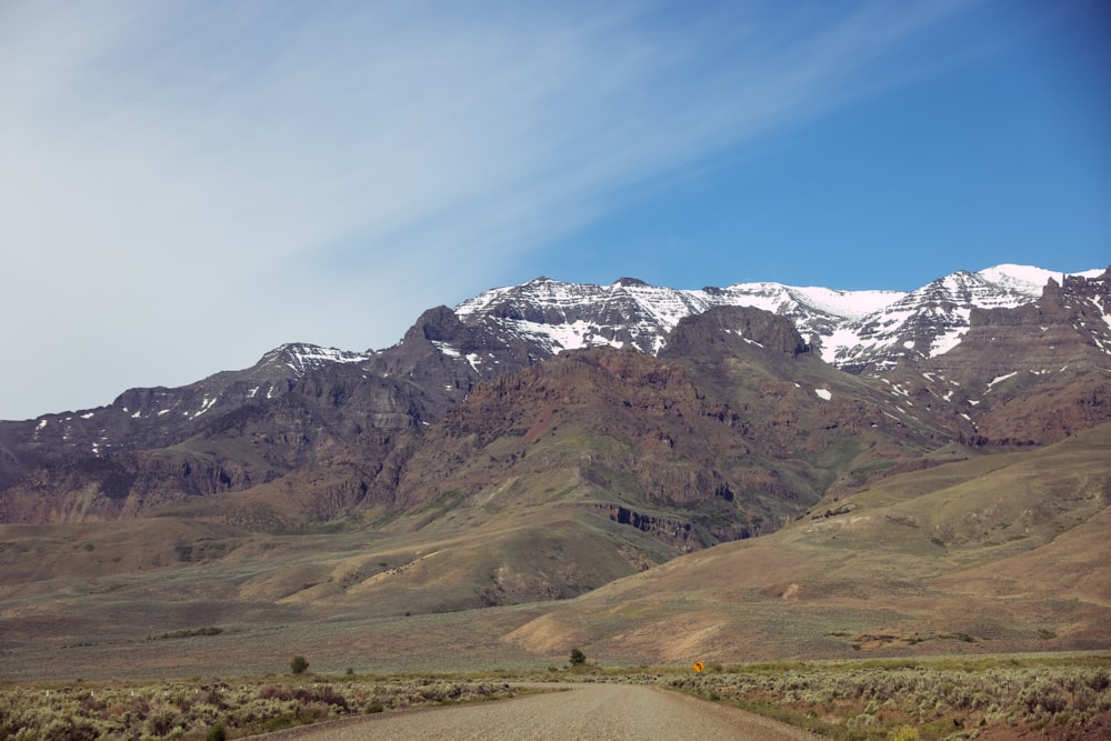 a dirt road in front of a mountain range