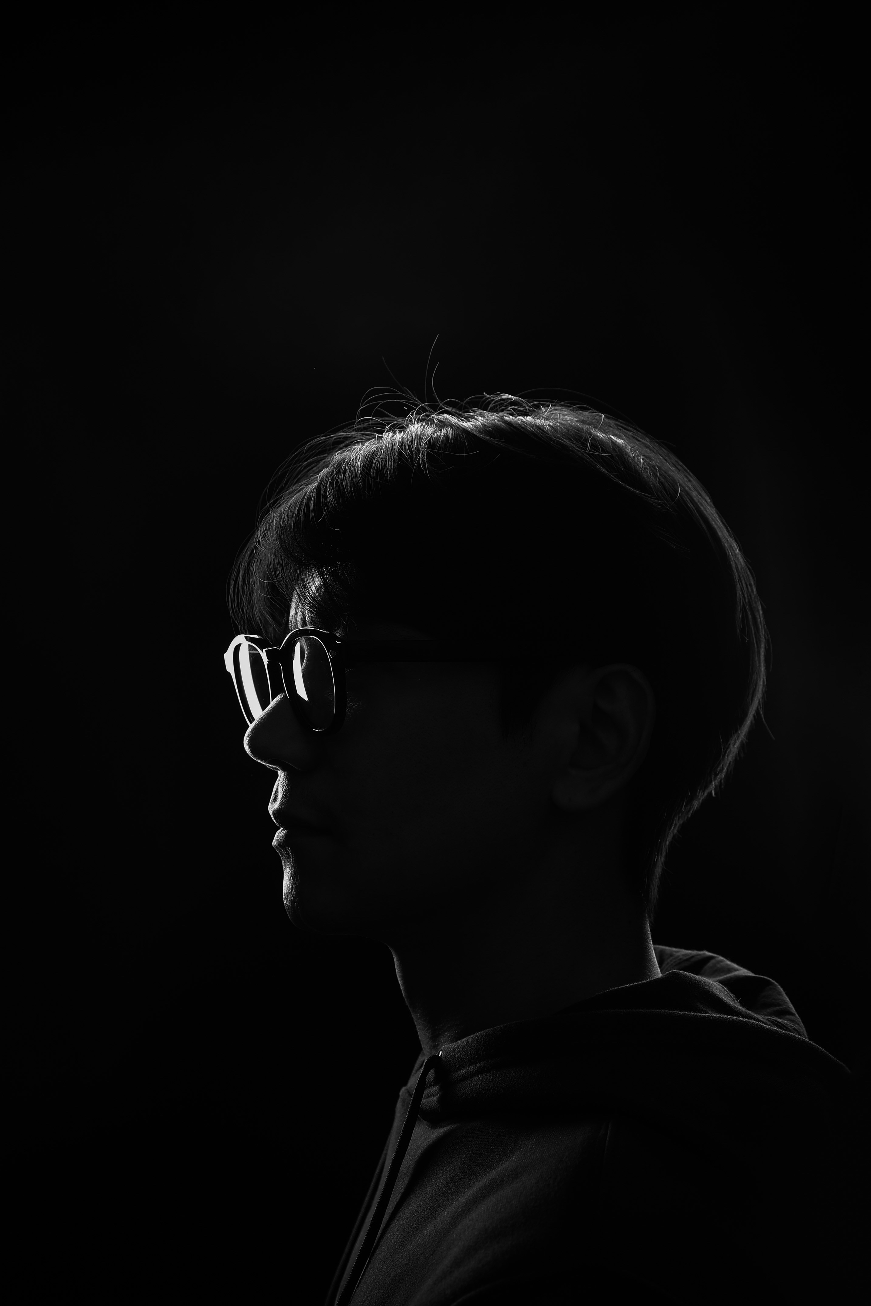 a man wearing glasses and a hoodie in the dark