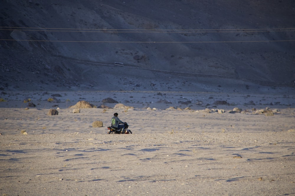 a man riding a motorcycle on top of a sandy beach