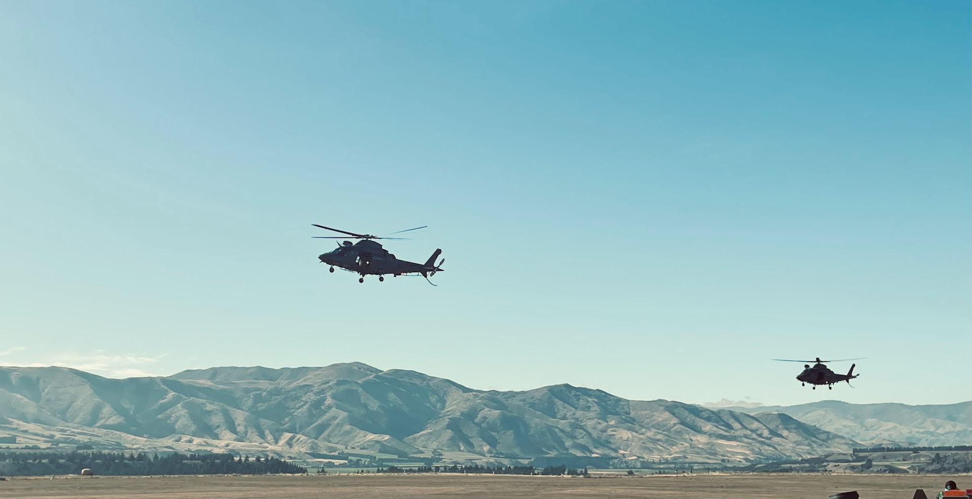 a couple of helicopters flying over a mountain range