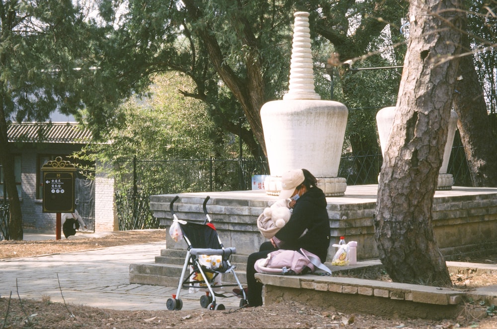 a woman sitting on a bench next to a baby stroller