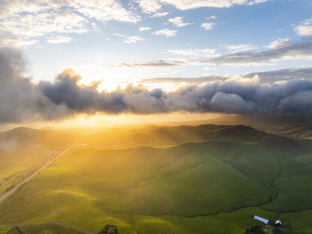 the sun is shining through the clouds over the hills