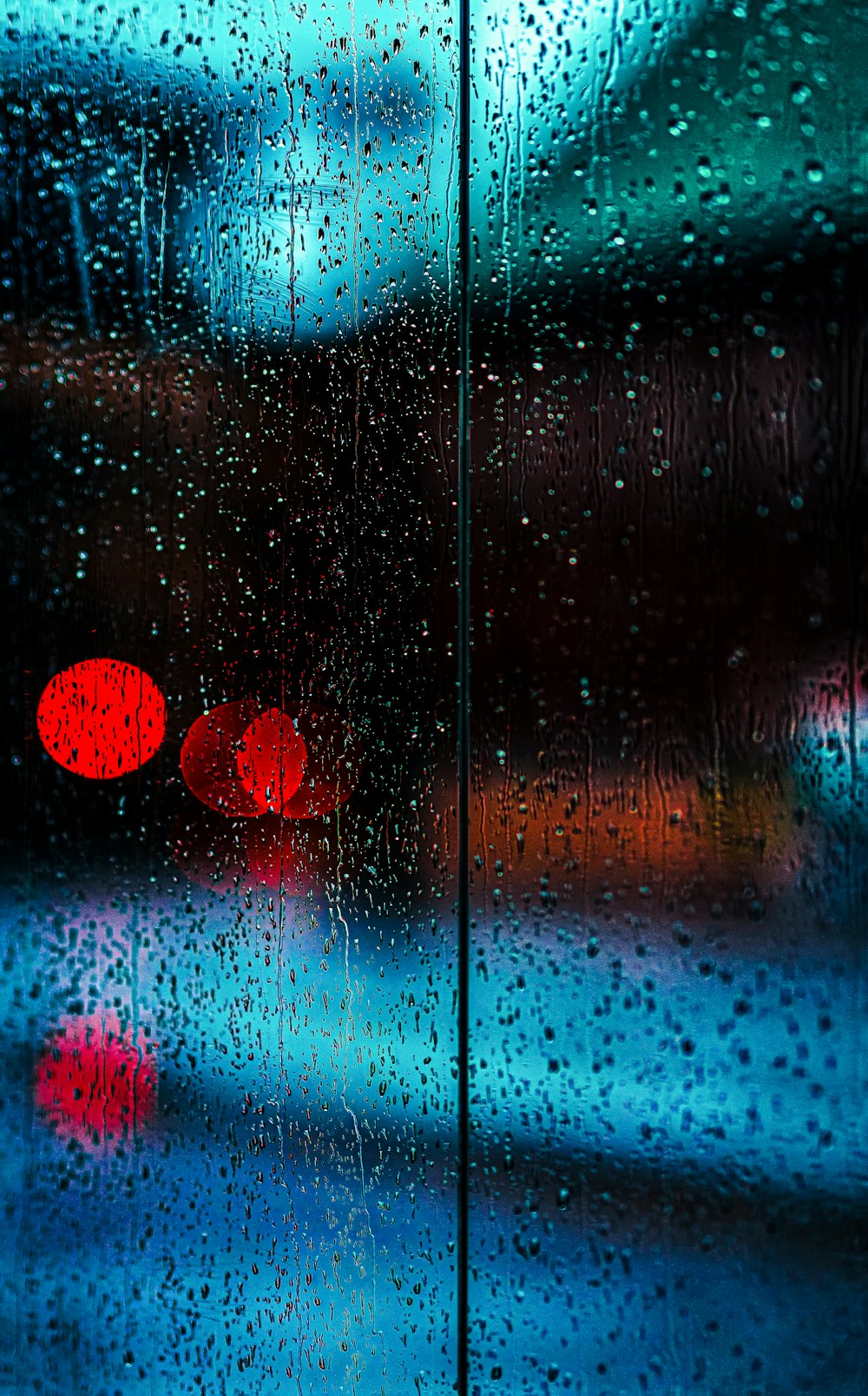 a traffic light sitting next to a window covered in rain