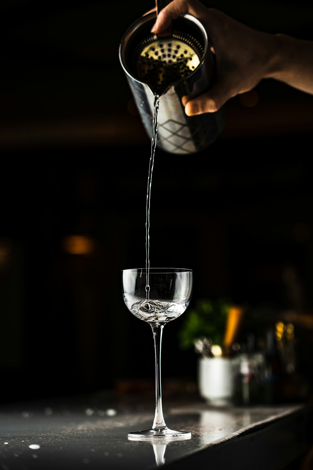 a person pouring a drink into a wine glass