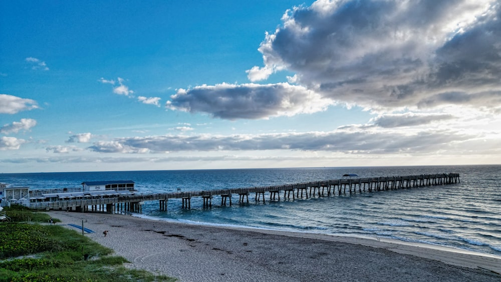 a pier on a beach near the ocean under a cloudy sky