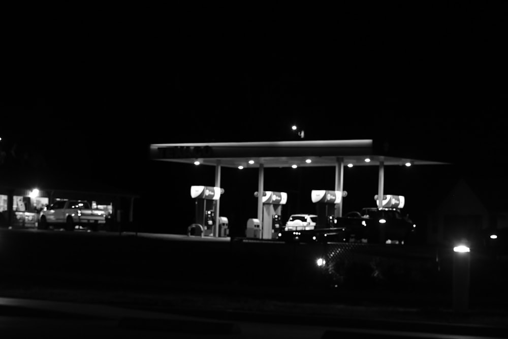 a black and white photo of a gas station at night