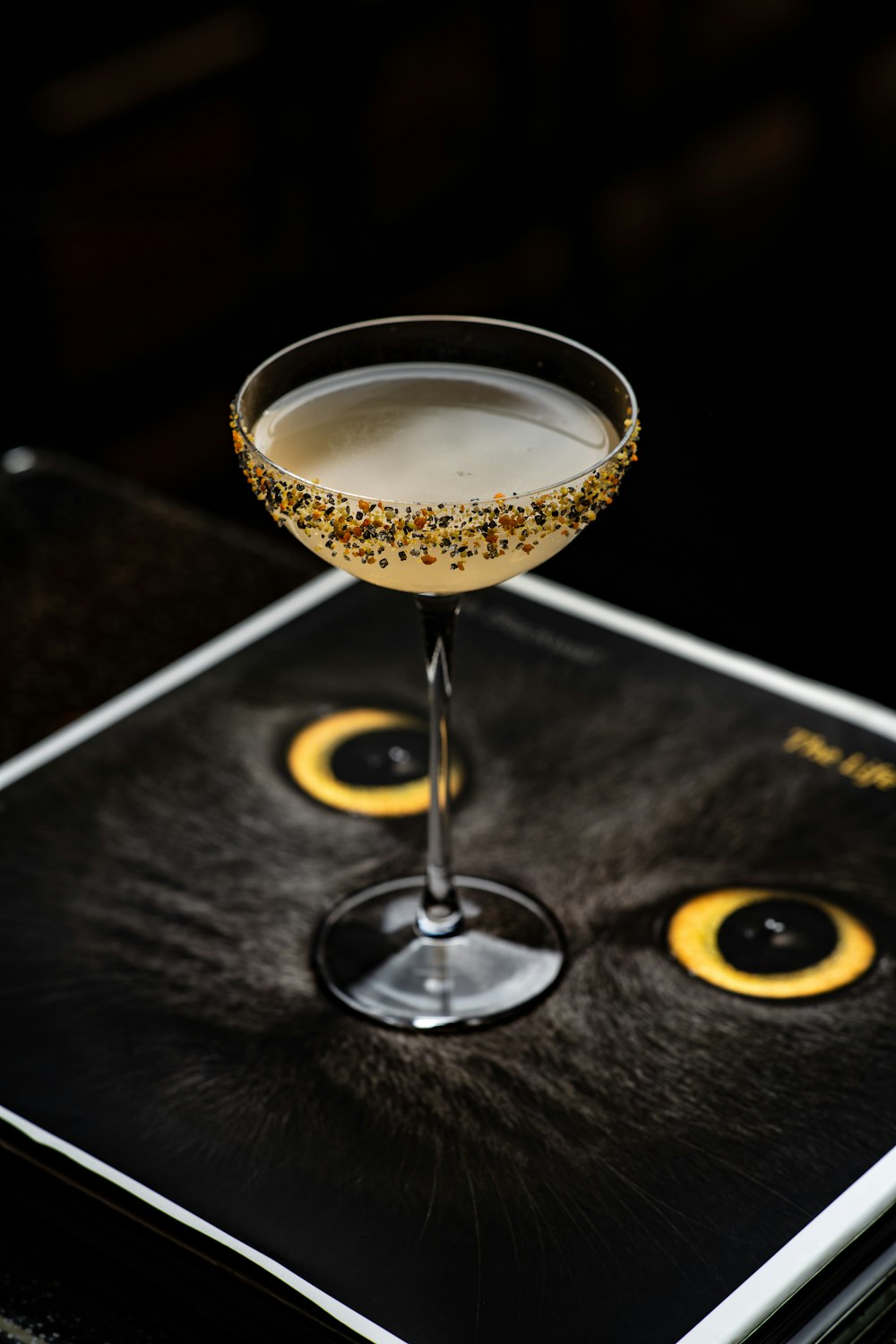 a black cat's face is on the side of a martini glass