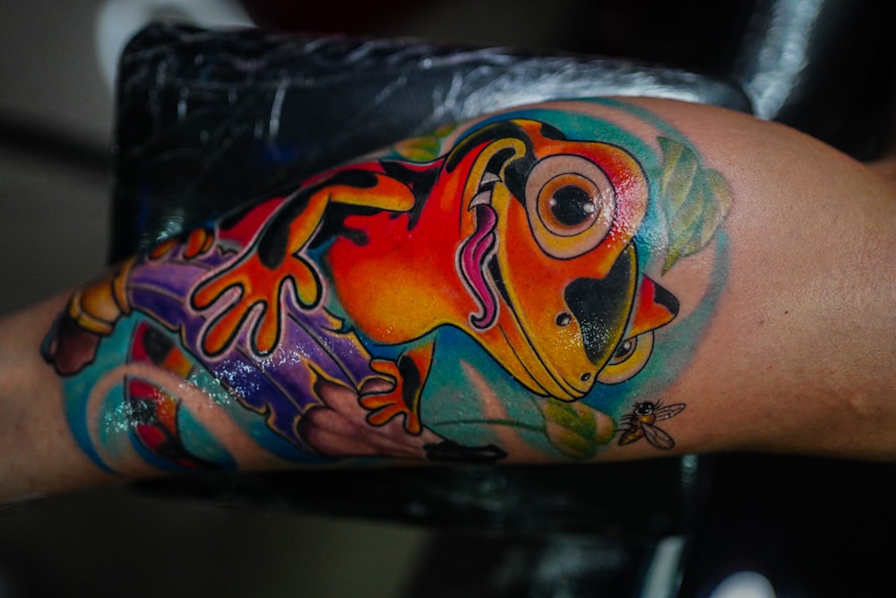 a colorful tattoo of a frog on the arm