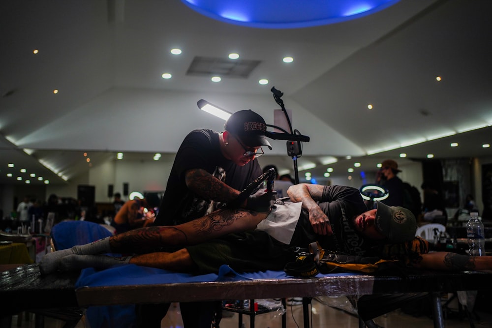 a man with a tattoo on his arm sitting on a table next to another man