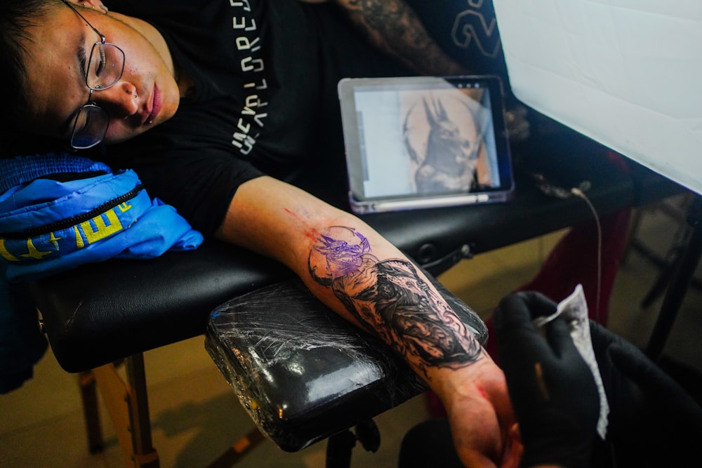 a man with a tattoo on his arm sitting in a chair