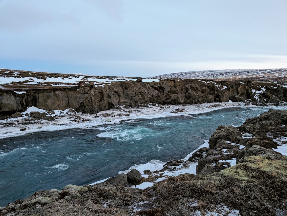 a body of water surrounded by snow covered rocks