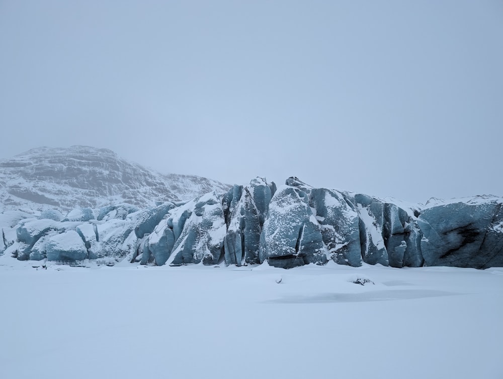a large rock formation covered in snow with a mountain in the background