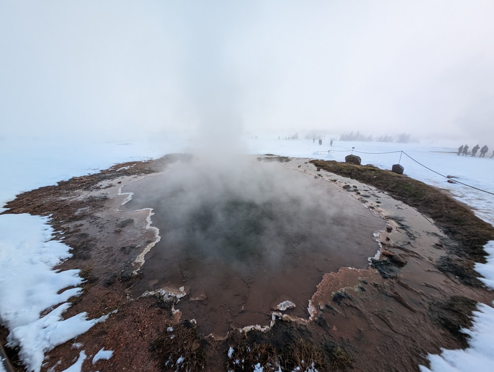 a snow covered landscape with a hot spring in the middle