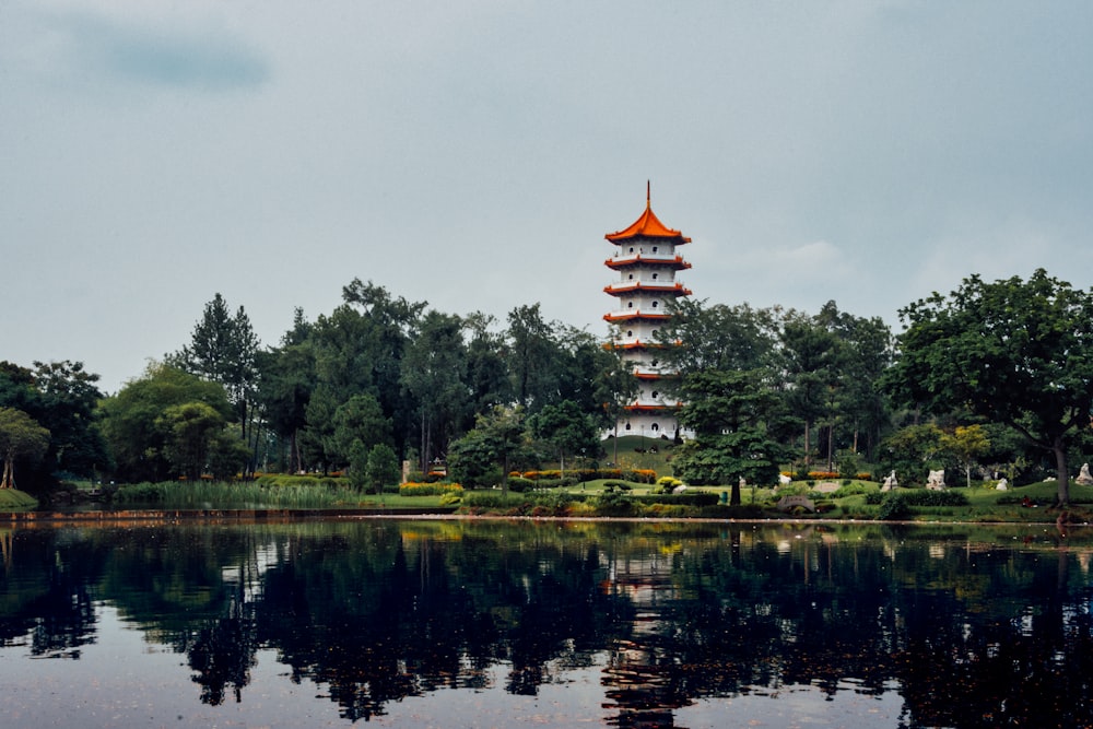 a tall pagoda sitting on top of a lake next to a forest